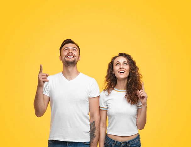 Excited couple pointing up with smile - Фото, изображение