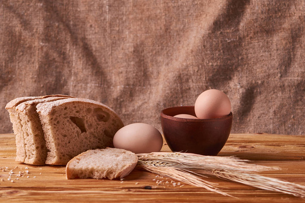 pain frais délicieux, concept de cuisson. Œufs dans un bol en argile et germes de blé sur une table en bois
 - Photo, image