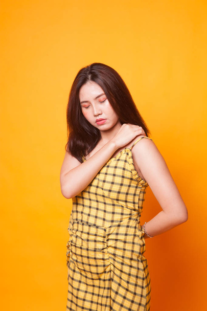 Young Asian woman got back pain on yellow background - Foto, afbeelding