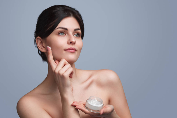 Beautiful woman applying moisturizing cream - Fotó, kép