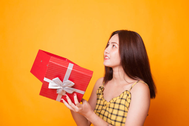 Young Asian woman open a gift box on yellow background - Fotó, kép