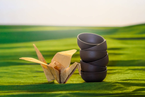 Tres tazas de cerámica y una grúa de origame en el fondo verde, vista cercana
 - Foto, Imagen