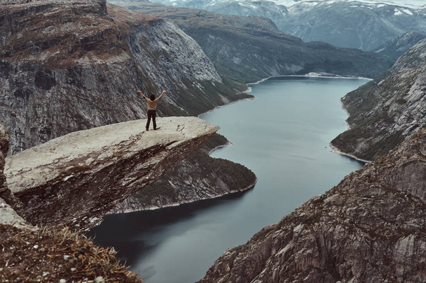 Tourist woman standing in the Trolltunga and enjoys the beautiful view of the Norwegian fjord. - Photo, Image