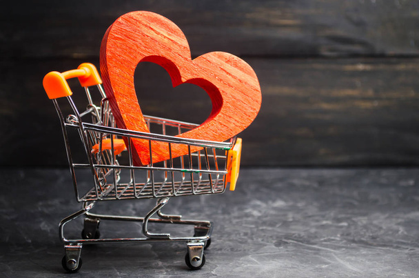 red heart in the supermarket trolley. concept of buying love. Valentine's Day. yellow background. Love of shopping. Favorite store. Buy love and happiness. Intimate services for money - Foto, Imagem