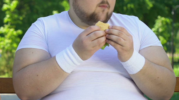 Zwakke-gewild man vette hamburger eten na de training, slechte gewoonten, fastfood - Video