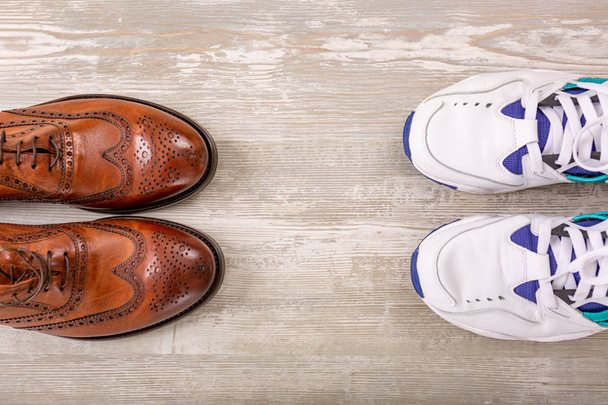 Мужская классическая коричневая кожаная обувь и кроссовки на деревянном полу. Мужчины в коричневой обуви
. - Фото, изображение