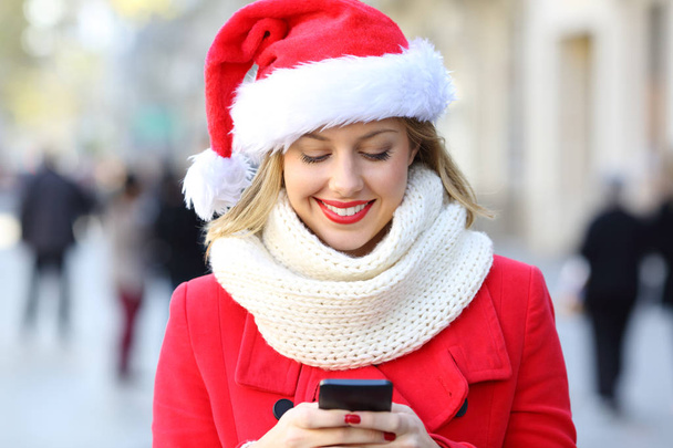 Передній вигляд щасливої жінки, що надсилає текст телефону на Різдво на вулиці
 - Фото, зображення