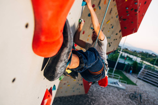 Uomo che indossa corda di sicurezza, arrampicata su una parete di arrampicata molto alta
 - Foto, immagini
