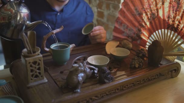 Facet wlewa ciepłą wodę do czajnika. Chińska ceremonia herbaty - Materiał filmowy, wideo