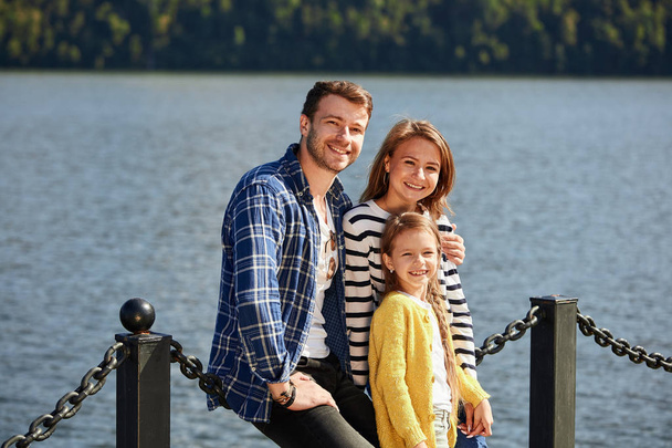 Happy Family looking at camera while posing on pier at quiet lake - Фото, зображення