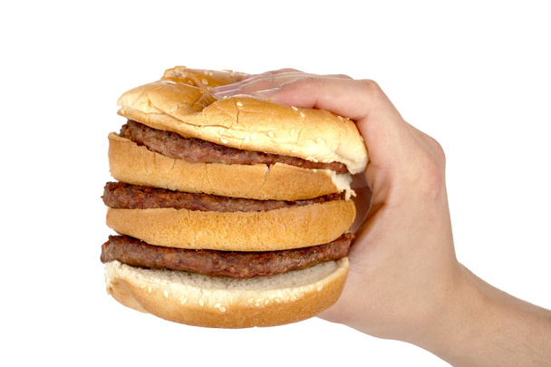 a hand slightly pressing the tall burger sandwich - Φωτογραφία, εικόνα