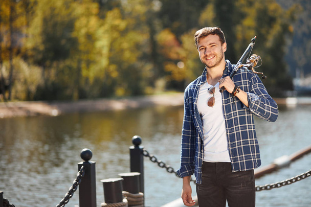 jovem pescador com vara e óculos de sol pesca no lago
 - Foto, Imagem