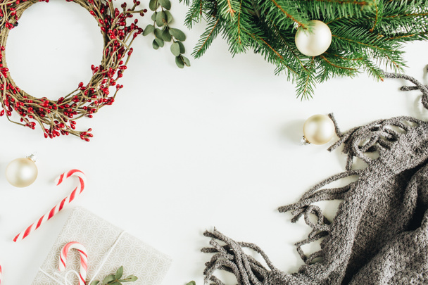 クリスマスの装飾の作ったコピー スペース フレーム モックアップ: モミの枝と赤い果実、お菓子、毛布、白い背景のユーカリのリース フレーム。フラット横たわっていた、トップ ビュー. - 写真・画像