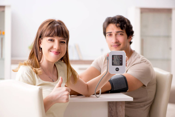 Дружина перевіряє чоловіків кров'яний тиск
   - Фото, зображення