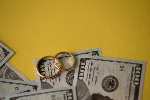 Golden wedding rings on dollars bill background. Divorce or infidelity concept - Zdjęcie, obraz
