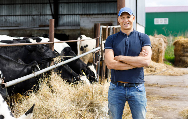 Agricultor en granja con vacas lecheras
 - Foto, Imagen