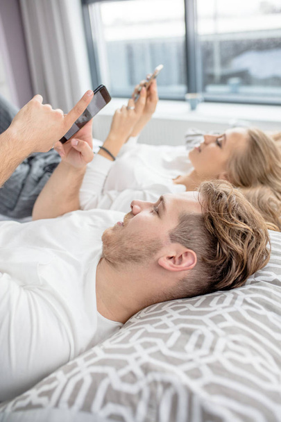 nice young people are surfing the Internet while resting on the bed - Фото, зображення