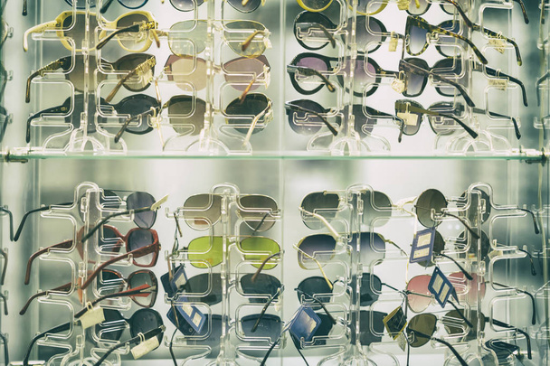 Sunglasses on glass shelves in a shop window, a summer accessory - Fotó, kép