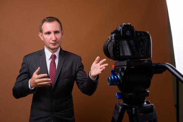 Studio shot of businessman against brown background - Foto, imagen