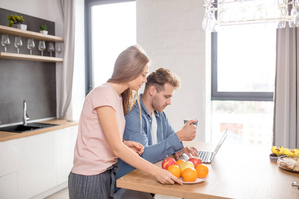 young couple watching video from the laptom in the kitchen with modern interior - Foto, Imagem