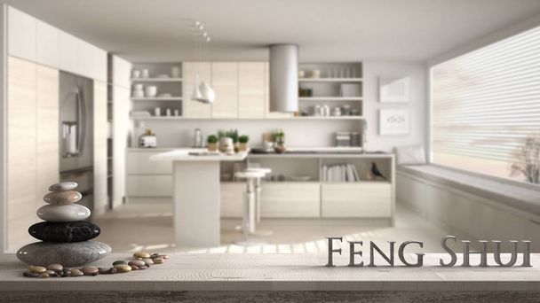 Holz Vintage-Tischregal mit Kieselsteinbalance und 3D-Buchstaben machen das Wort Feng Shui über verschwommene weiße Küche mit Holzdetails und Panoramafenster, Zen-Konzept Innenarchitektur - Foto, Bild