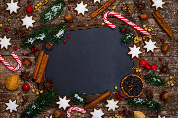 Sfondo natalizio su lavagna nera con biscotti di pan di zenzero a stella e decorazioni natalizie. Focus selettivo
. - Foto, immagini