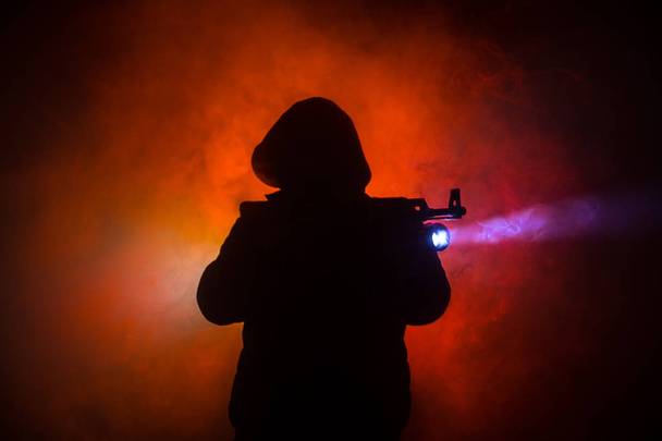Silhouette di uomo con fucile d'assalto pronto ad attaccare su sfondo scuro tonica nebbia o pericoloso bandito tenendo la pistola in mano. Tiro terrorista con decorazione a tema arma
 - Foto, immagini