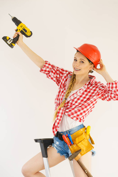 Woman wearing helmet using drill. Girl working at flat remodeling. Building, repair and renovation. - Fotoğraf, Görsel