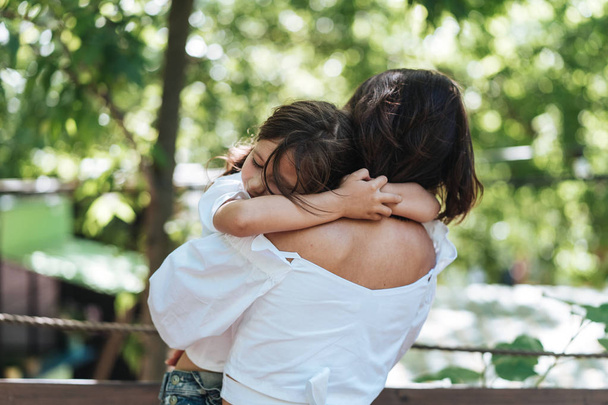 Νεαρή μητέρα αγκαλιάζει την κόρη της λίγο στο πάρκο - Φωτογραφία, εικόνα