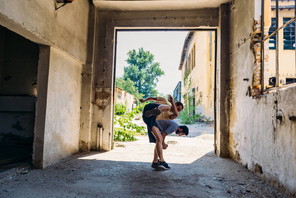 Two sporty friends in action while train together at abandoned factory - Photo, Image