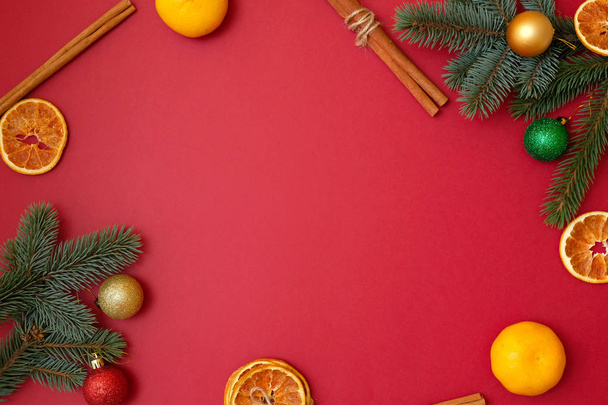 Christmas holidays composition on red background with copy space for your text. Xmas tree branches in the corners, dried oranges, cinnamon sticks. Xmas backdrop for greeting card. Flat lay, top view - Fotografie, Obrázek