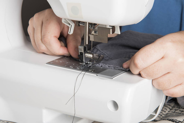 A Woman Using a modern Sewing Machine to repair clothing. - Foto, Bild