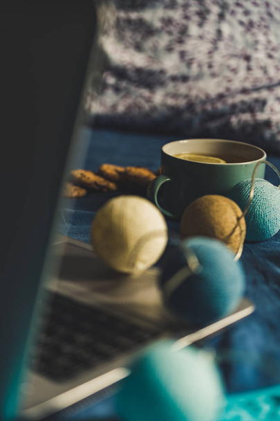 Tea with Lemon and Cookies with Chocolate Laying on Mattress - Christmas Decoration Light Balls and Grey Laptop Besides it, Vintage Look Edit - Photo, Image