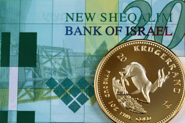 A macro image of a gold one ounce krugerrand with a 20 Israeli bill close up - Photo, Image