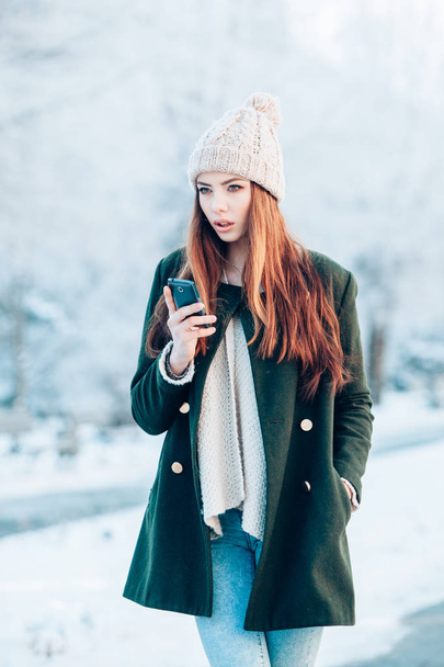 Young  woman smiling with smart phone and winter landscape . - 写真・画像
