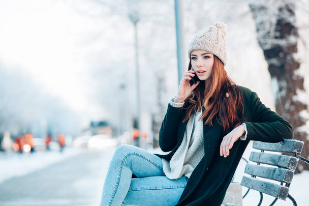Młoda kobieta uśmiechając się z inteligentnych telefonów i zimowy krajobraz . - Zdjęcie, obraz