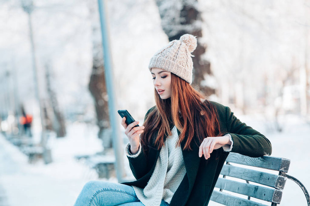 Mujer joven sonriendo con teléfono inteligente y paisaje de invierno
 . - Foto, imagen