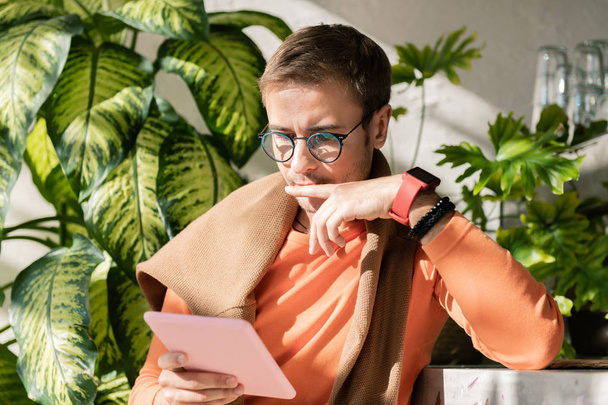 Modern successful entrepreneur wearing smart watch reading book on tablet - Foto, Imagen