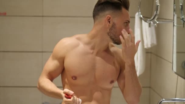 Handsome young man applying moisturizing cream - Filmagem, Vídeo