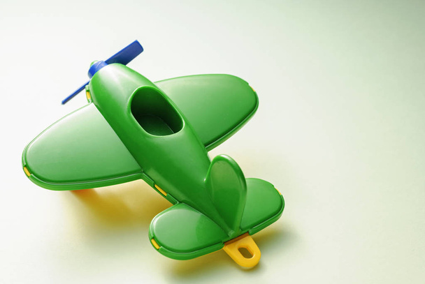 緑のグラデーション背景に子供のおもちゃ緑の飛行機 - 写真・画像