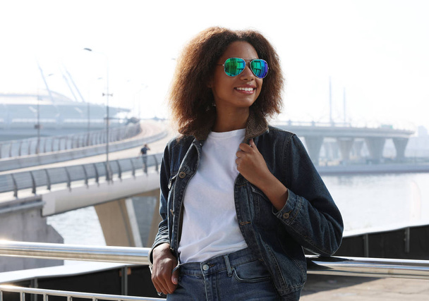 pretty woman wearing sunglasses with perfect teeth and dark clean skin having rest outdoors, smiling after received good positive news. - Fotoğraf, Görsel