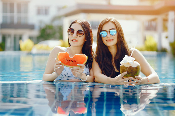 two girls having fruit by the pool - Photo, image