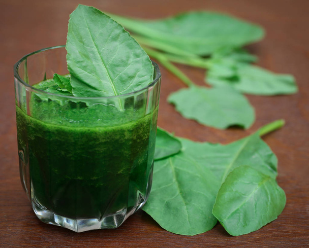 Mashed spinach smoothie in a glass on wooden surface - Foto, Bild