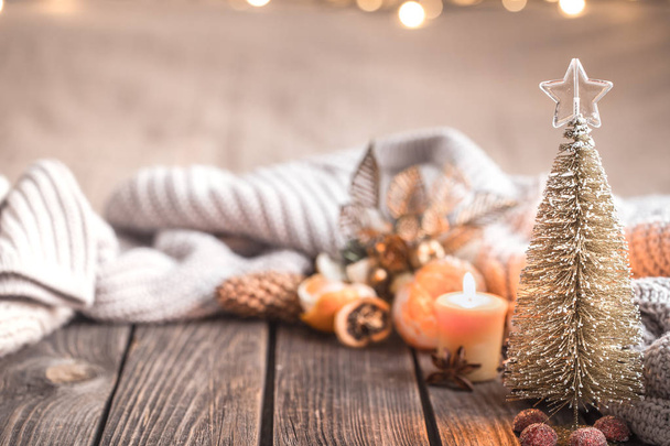 Праздничная уютная атмосфера Рождества с домашним декором и мандаринами на деревянном фоне, концепция домашнего комфорта
 - Фото, изображение