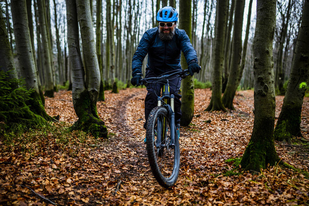 Maastopyöräilijä pyöräily syksyllä vuorilla metsämaisema. Mies pyöräilee MTB:n juoksuradalla. Ulkoilutoiminta
. - Valokuva, kuva