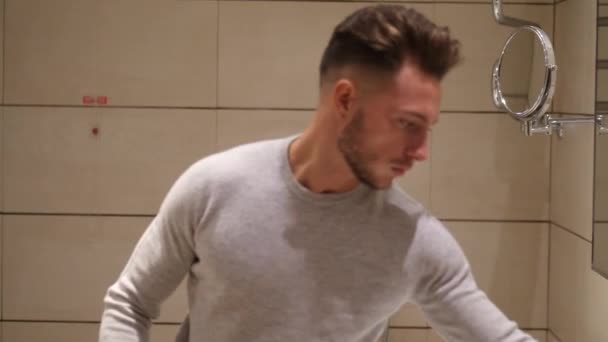 Young man in bathroom, spraying cologne or perfume - Video
