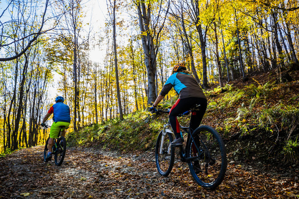 Cycling woman and man at Beskidy mountains autumn forest landscape. Couple riding MTB enduro track. Outdoor sport activity. - Fotografie, Obrázek