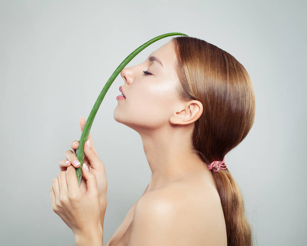 schöne Frau mit gesundem Haar und klarer Haut mit grünem Aloe-Vera-Blatt - Foto, Bild