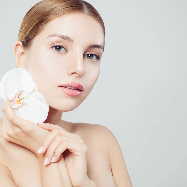 Mooie wellness vrouw met gezonde huid en bloem op witte achtergrond, Wellness schoonheid, visagie, gezichtsbehandeling en wellness-concept  - Foto, afbeelding