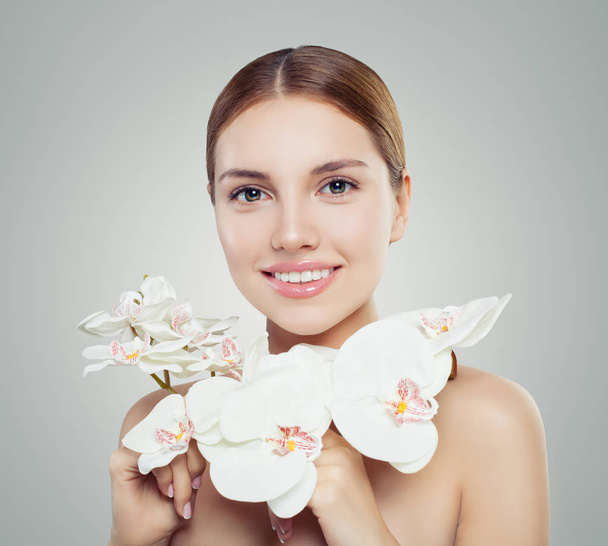 Natural beauty. Attractive woman with healthy skin and orchid flower. Cosmetology, facial treatment and wellness female portrait - Photo, Image